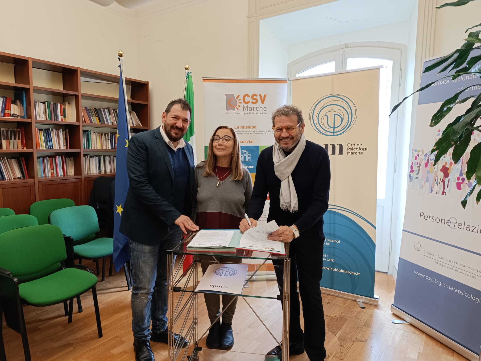 Il momento della firma dell'accordo, con i rappresenentati di Csv e Opm attorno a un tavolo col documento dispiegato.