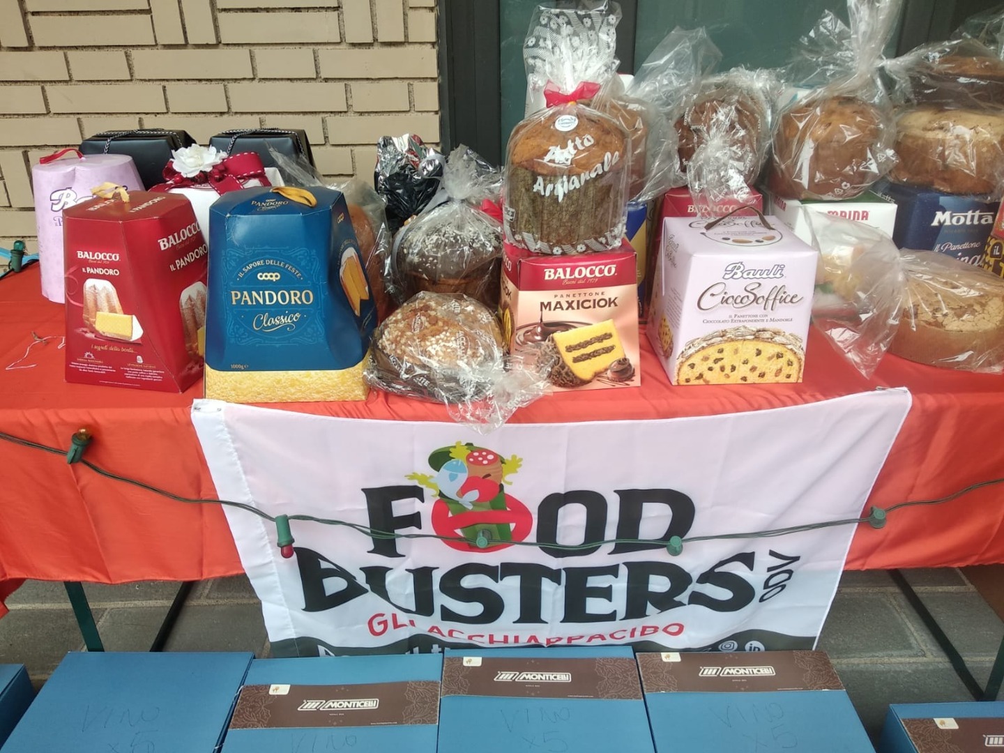 Panettoni, pandori e altro cibo natalizio su un banchetto con la bandiera di Foodbusters